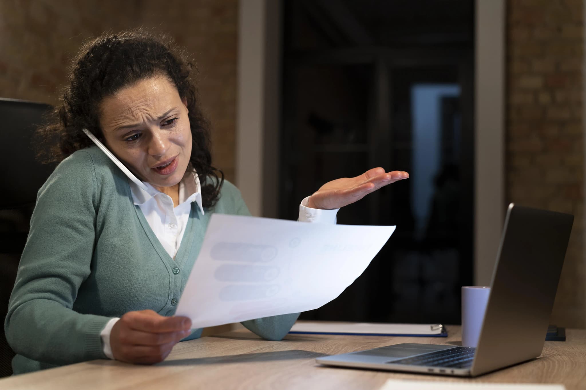 An anxious woman on a phone call holding and looking at a paper report